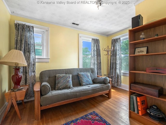 sitting room with hardwood / wood-style floors, a textured ceiling, and ornamental molding