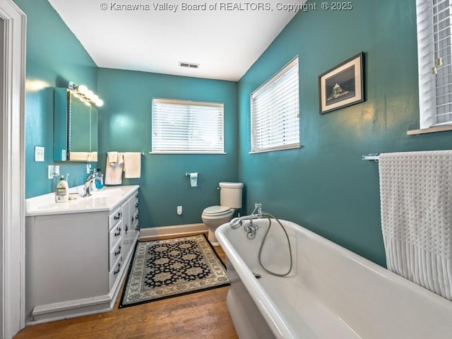 bathroom with hardwood / wood-style floors, vanity, toilet, and a washtub