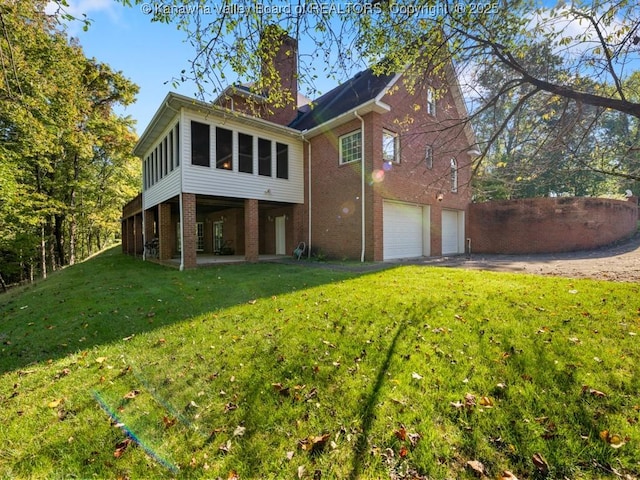 rear view of property with a sunroom, a yard, and a garage