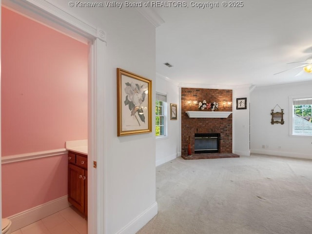 unfurnished living room with light colored carpet, a brick fireplace, ceiling fan, and crown molding