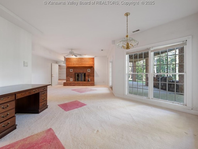 unfurnished living room featuring ceiling fan with notable chandelier, a fireplace, and light carpet