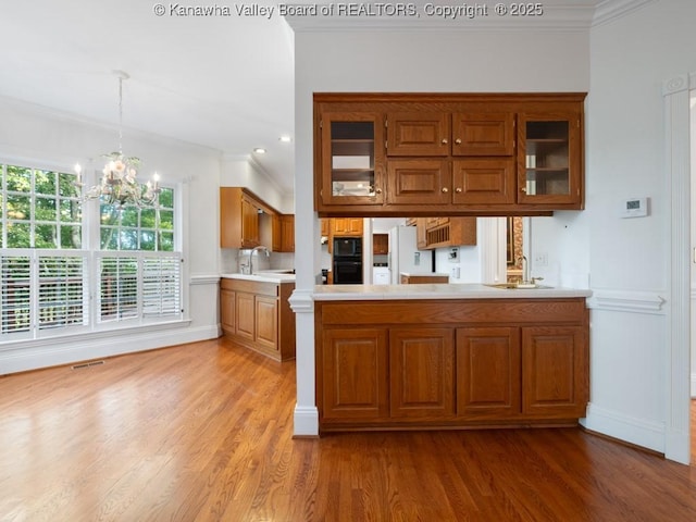 kitchen with sink, an inviting chandelier, kitchen peninsula, crown molding, and pendant lighting