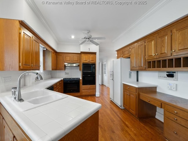 kitchen with tile countertops, white refrigerator with ice dispenser, backsplash, sink, and ceiling fan