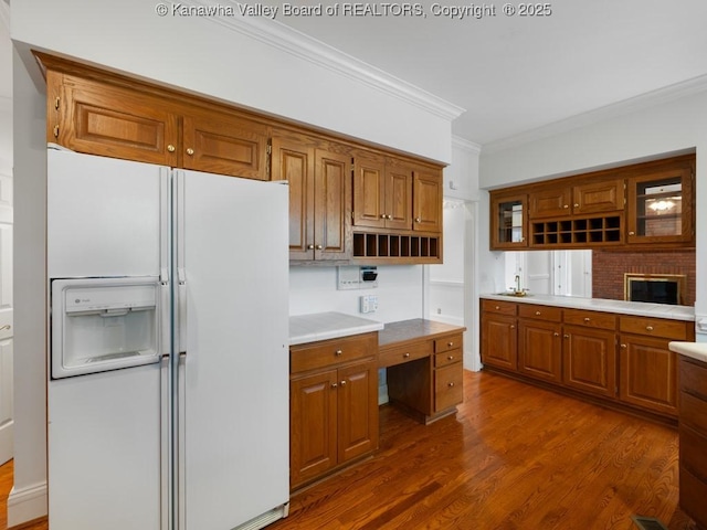 kitchen with a fireplace, dark hardwood / wood-style flooring, white fridge with ice dispenser, and crown molding