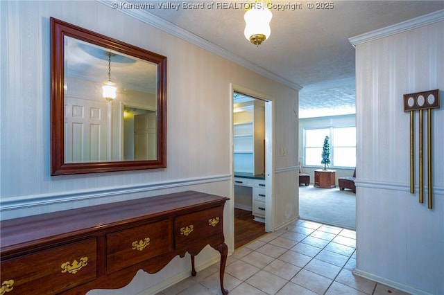 corridor featuring crown molding, light tile patterned flooring, and a textured ceiling