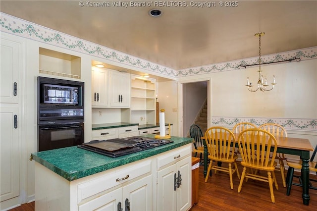 kitchen featuring black appliances, pendant lighting, an inviting chandelier, a center island, and white cabinetry