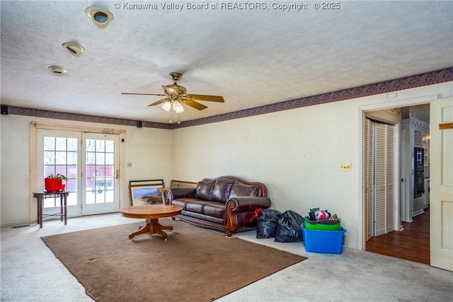 carpeted living room featuring a textured ceiling and ceiling fan