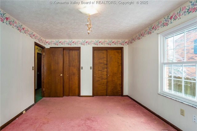 unfurnished bedroom featuring a textured ceiling, carpet, and two closets