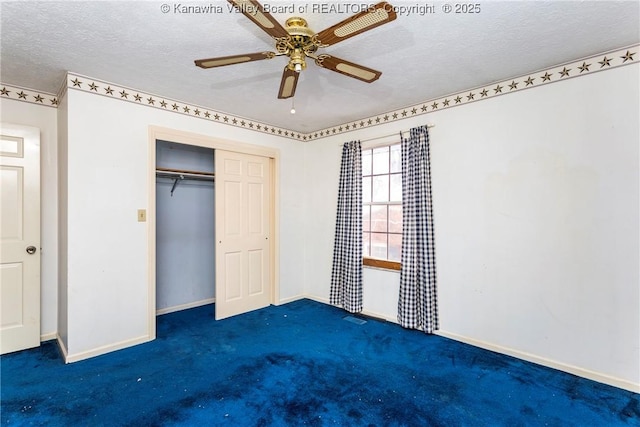 unfurnished bedroom with dark colored carpet, a textured ceiling, a closet, and ceiling fan