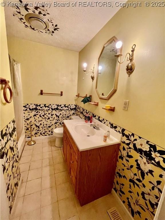 bathroom featuring walk in shower, vanity, a textured ceiling, tile patterned flooring, and toilet