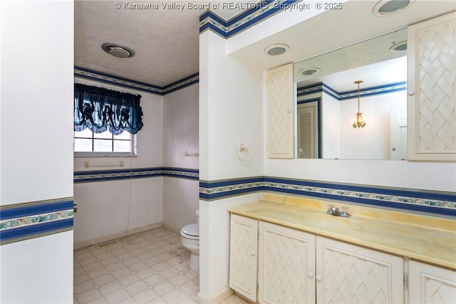 bathroom featuring vanity, a textured ceiling, toilet, and ornamental molding