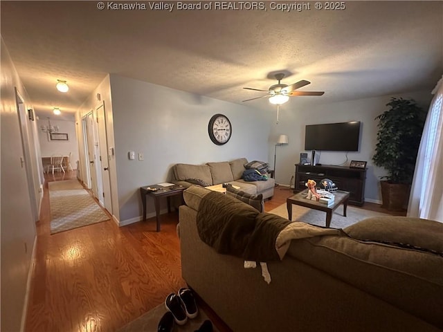 living room with a textured ceiling, light wood-type flooring, and ceiling fan