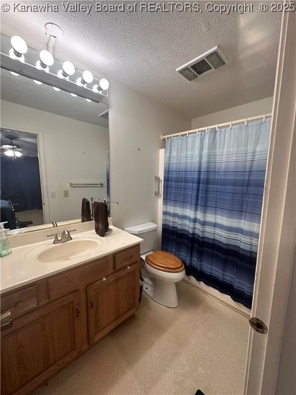 bathroom with walk in shower, vanity, a textured ceiling, and toilet