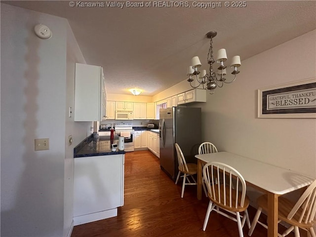 kitchen with white cabinetry, dark wood-type flooring, a chandelier, white appliances, and decorative light fixtures