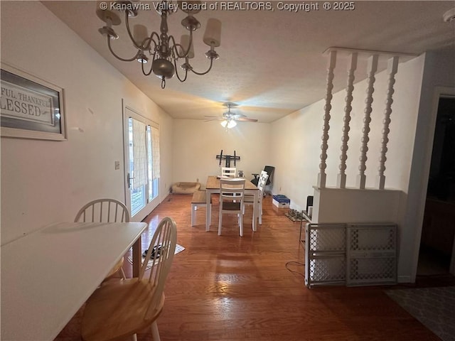 dining room featuring a textured ceiling, wood-type flooring, and ceiling fan with notable chandelier