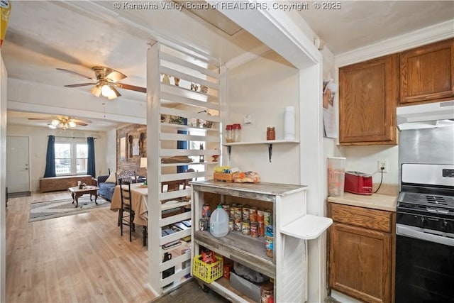 kitchen featuring crown molding, ceiling fan, stainless steel gas stove, and light hardwood / wood-style floors