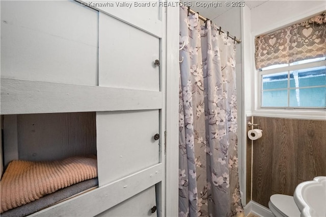 bathroom featuring toilet and wood walls