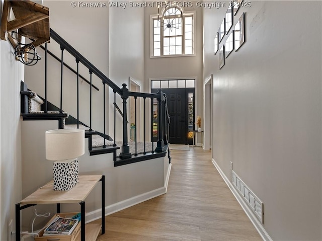 entryway with a towering ceiling and light hardwood / wood-style flooring