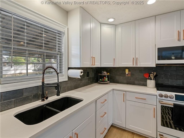 kitchen with sink, white cabinets, and white appliances