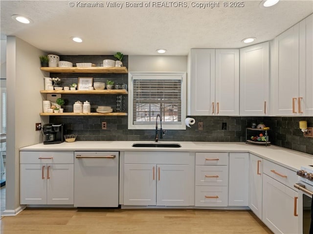 kitchen with white cabinetry, stainless steel dishwasher, light hardwood / wood-style floors, and sink