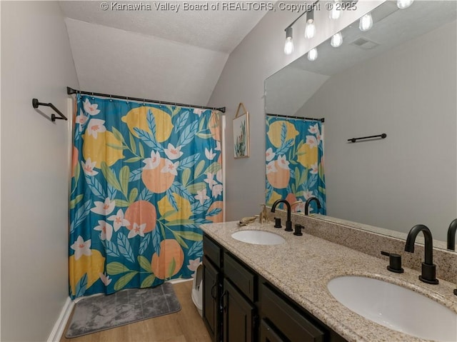 bathroom featuring hardwood / wood-style floors, vanity, a textured ceiling, and vaulted ceiling