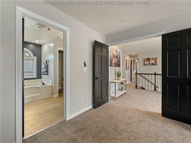 hallway with carpet flooring and a textured ceiling