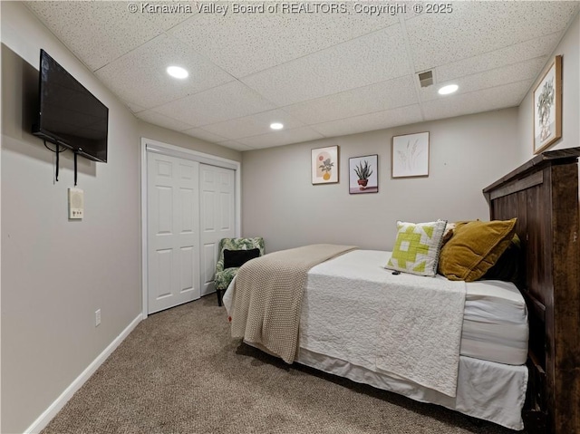 bedroom featuring carpet, a drop ceiling, and a closet