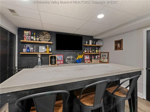 bar with a paneled ceiling and hardwood / wood-style flooring