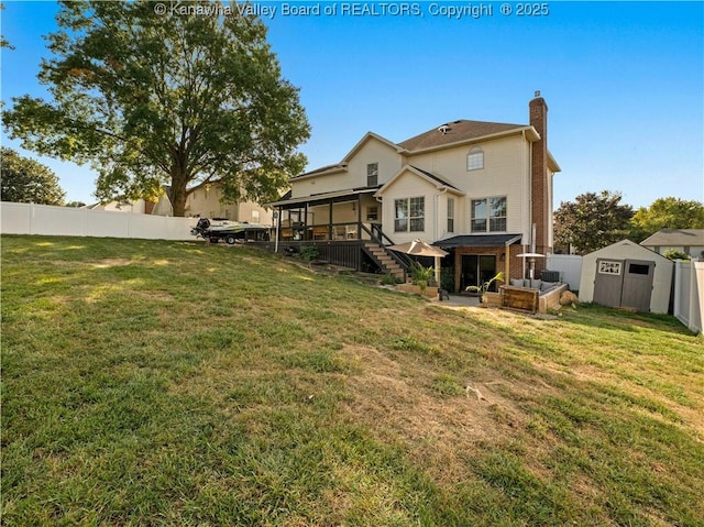 back of house with a lawn, a sunroom, a patio area, and a shed