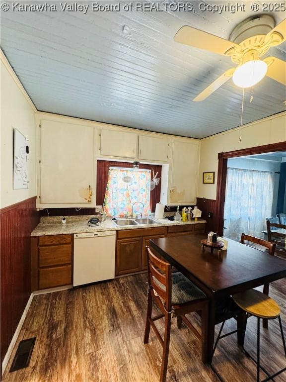 kitchen with ceiling fan, dishwasher, wood walls, sink, and dark hardwood / wood-style flooring