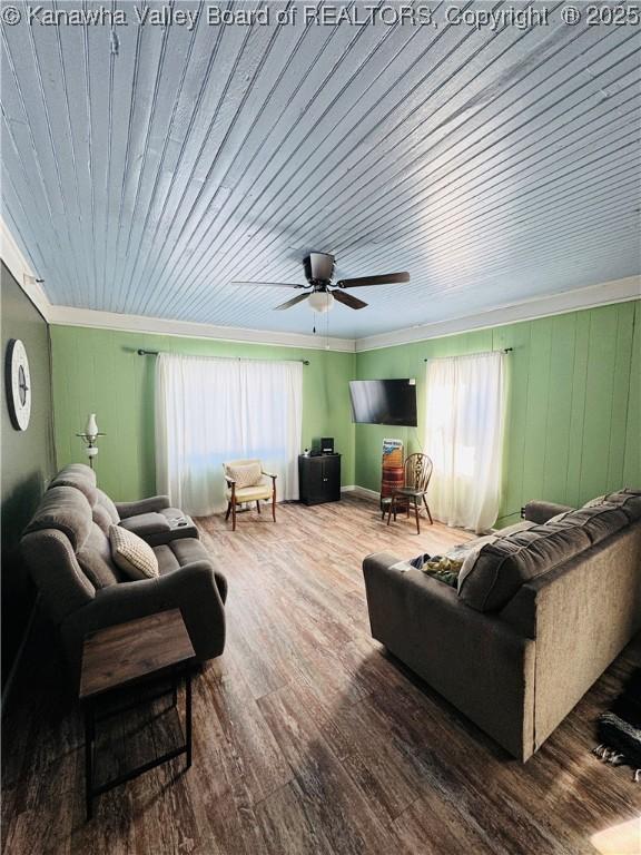 living room featuring ceiling fan, wood-type flooring, ornamental molding, and wooden ceiling