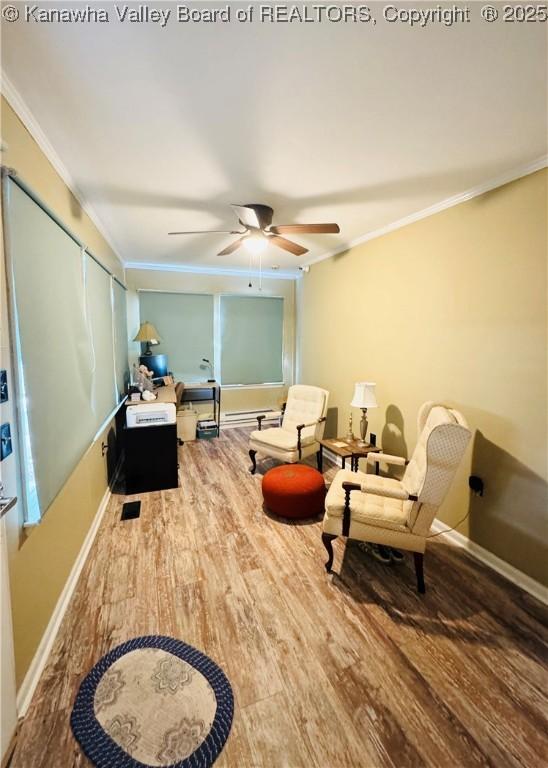 sitting room with ceiling fan, wood-type flooring, a baseboard heating unit, and crown molding