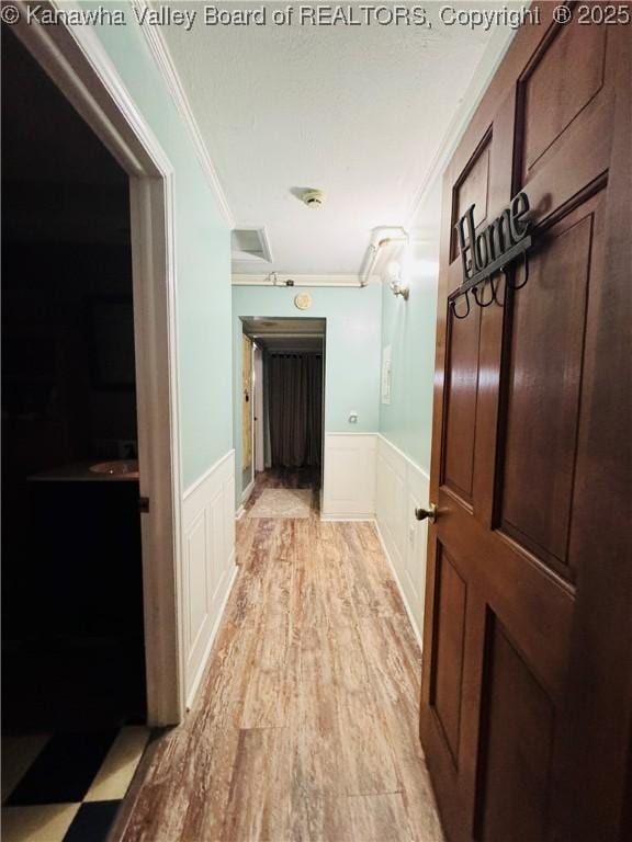 hallway featuring light hardwood / wood-style floors and crown molding