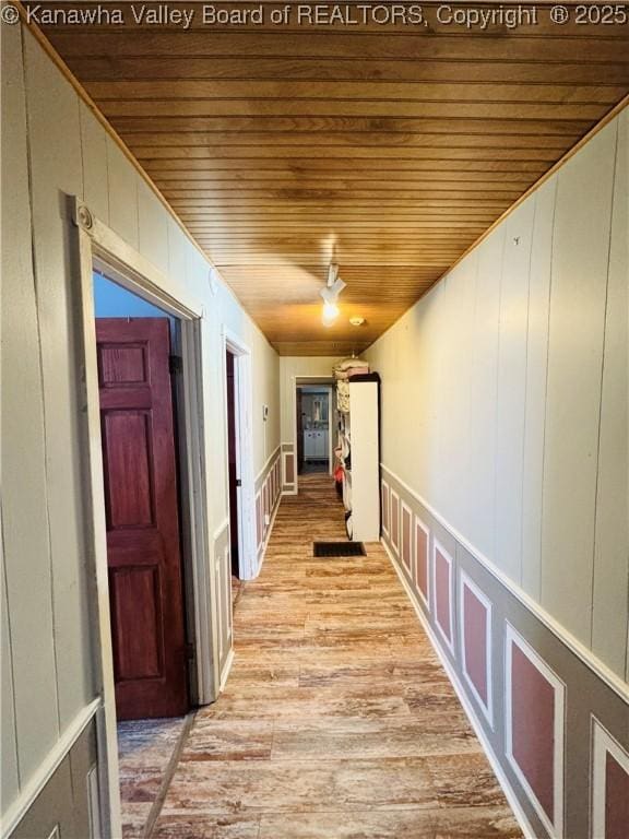 corridor featuring light wood-type flooring and wooden ceiling