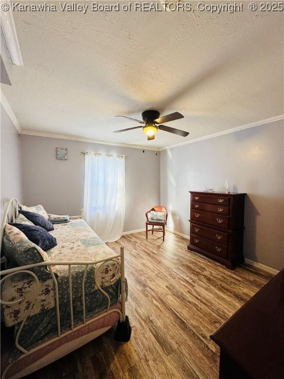 bedroom with a textured ceiling, ceiling fan, crown molding, and wood-type flooring