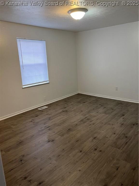 unfurnished room with dark wood-type flooring