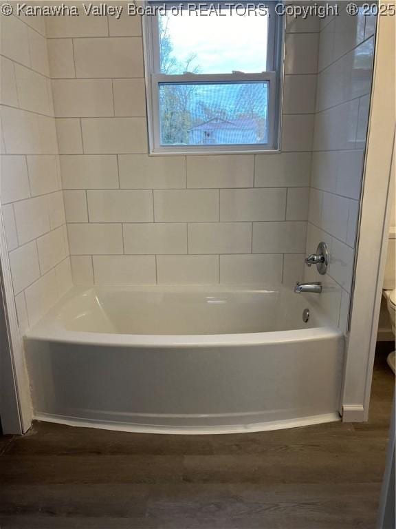 bathroom featuring wood-type flooring, toilet, and shower / washtub combination