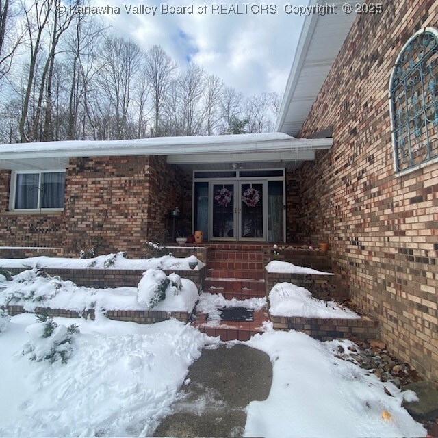 snow covered property entrance featuring french doors