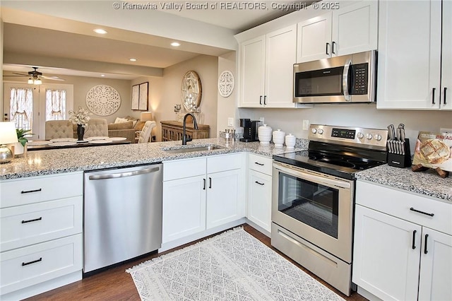 kitchen featuring sink, white cabinetry, appliances with stainless steel finishes, dark hardwood / wood-style flooring, and ceiling fan