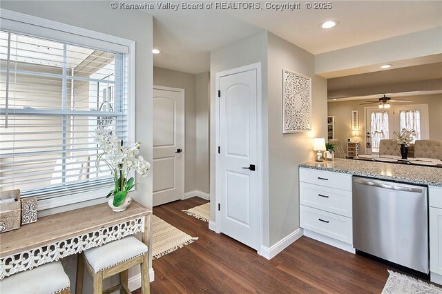 kitchen with white cabinets, stainless steel dishwasher, ceiling fan, light stone counters, and dark wood-type flooring