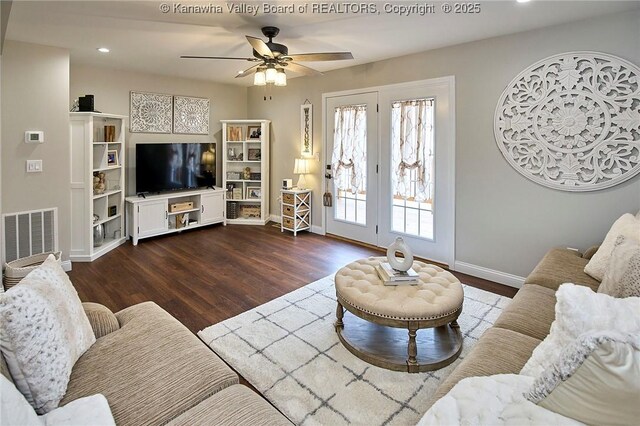 living room featuring dark wood-type flooring and ceiling fan