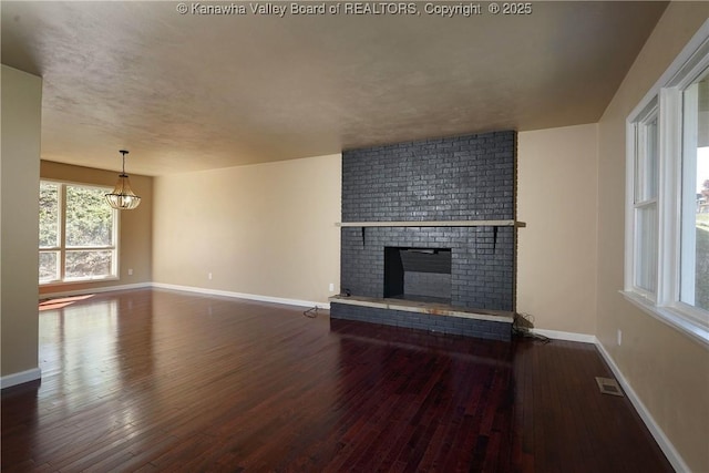 unfurnished living room with dark hardwood / wood-style flooring and a brick fireplace