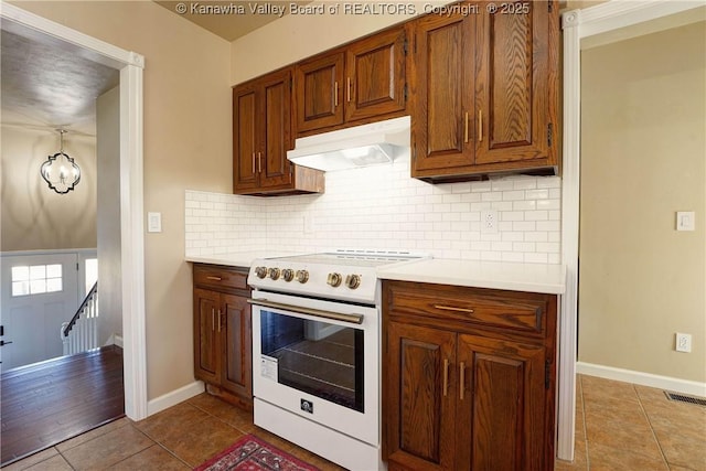 kitchen with white range with electric stovetop, decorative backsplash, and light tile patterned flooring