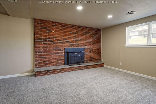 unfurnished living room with a wood stove and carpet