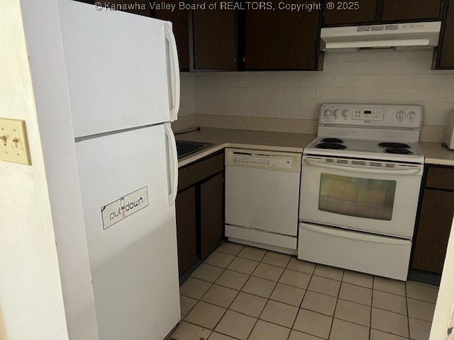 kitchen featuring white appliances, light tile patterned floors, sink, and dark brown cabinetry