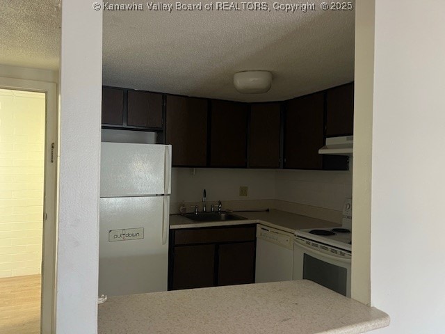 kitchen with white appliances, a textured ceiling, sink, and dark brown cabinetry