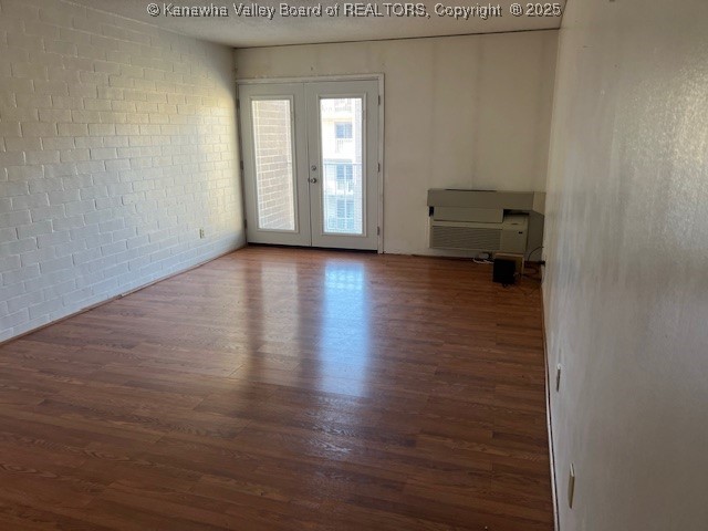 spare room with brick wall, french doors, and dark hardwood / wood-style flooring