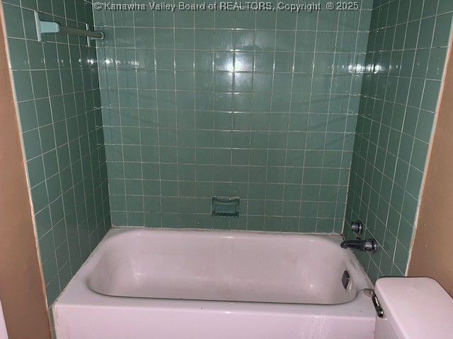 bathroom featuring toilet and tiled shower / bath