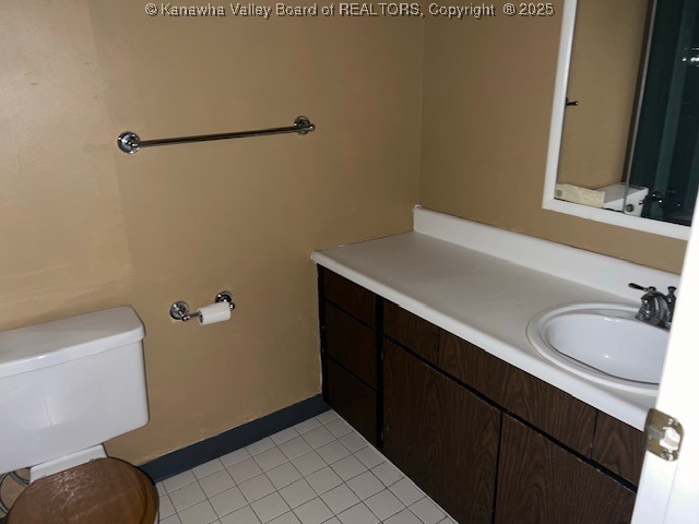 bathroom with toilet, vanity, and tile patterned floors