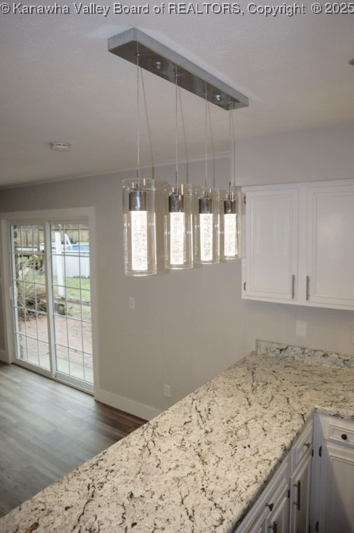 kitchen with decorative light fixtures, dark hardwood / wood-style floors, light stone counters, and white cabinetry